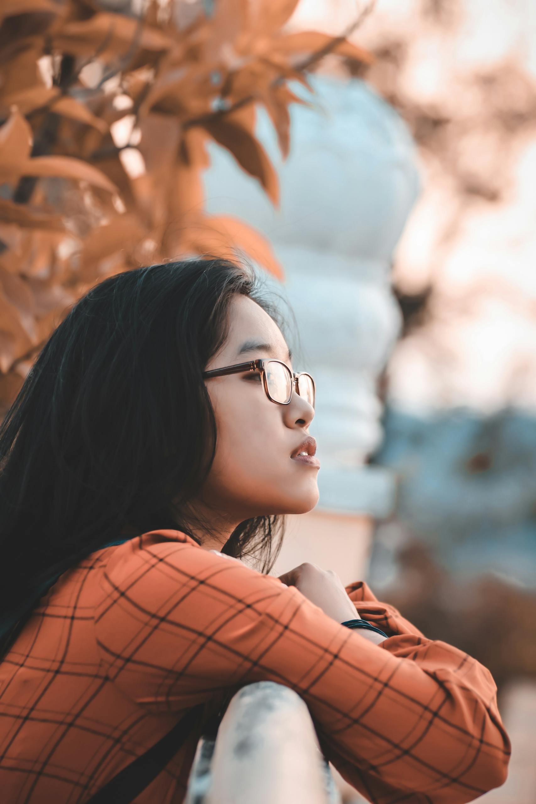 A young woman in glasses enjoying the outdoors with an autumn ambiance.