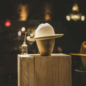 Sophisticated hat displayed on wooden stand in an Austin, TX shop window.